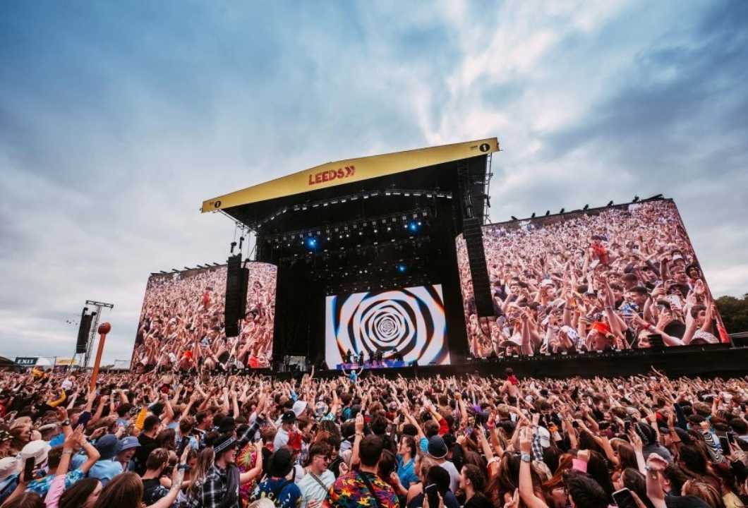 A large crowd in front of a stage at a festival.