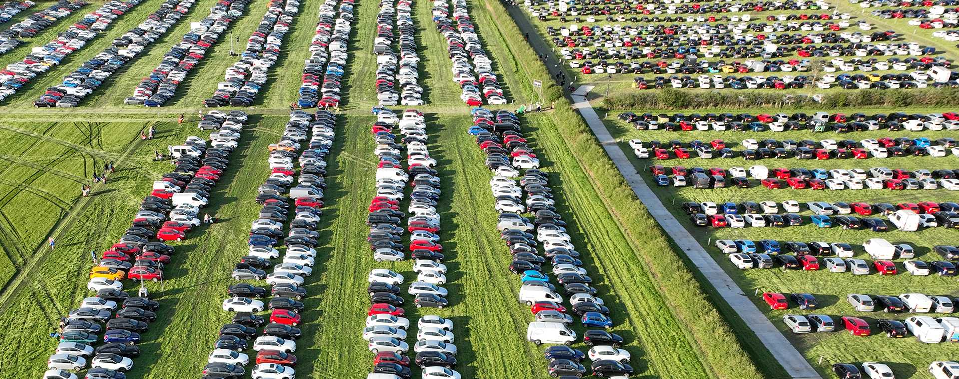 An aerial view of cars parked in a field.