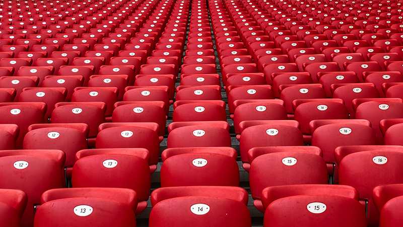 Rows of red plastic seats in the stands of a football stadium